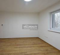 An empty room with wood-patterned flooring, a window, and light-colored walls in a family house.