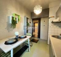 A kitchen in a 3-room apartment with a table, chairs, and decorations, ideal for dining.