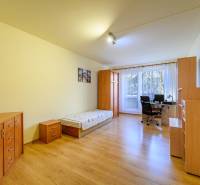 Room in a 2-room apartment; bed, desk, wardrobes, floor with wood decor.