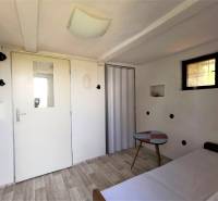 Simple interior, white cottage, small table, light floor, door with window, recreational area.