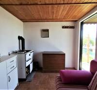 In the chat kitchen, there is a stove, a cabinet, a pink sofa, and a view of the garden.