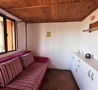 A cabin interior with a wooden ceiling, a comfortable couch, and white storage furniture.