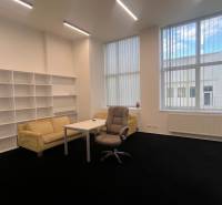 Offices with black carpet, furniture, shelving systems, and large windows.