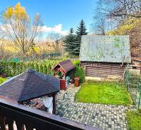 A garden by the cottage in Partizánske with a gazebo and trees in the background.