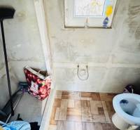A bathroom in a cabin with a wooden decor floor, a toilet, and a window.