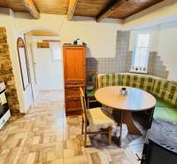A rustic kitchen in a cottage with a gas stove and a corner sofa.