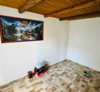 Living room in a cabin with a wooden ceiling, floor with wooden decor, and a painting on the wall.