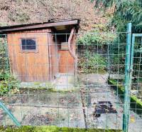 A wooden cabin enclosed by a metal fence in the forest near Partizánske.