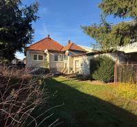 A family house in Machulince with a red tiled roof, a garden, and mature trees.