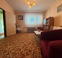 Living room in a family house with carpeted floor, furniture, and curtains.