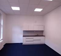 Offices with a kitchenette and blue carpet, white walls, and a large window.