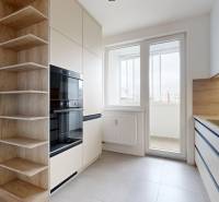 A kitchen in a 3-room apartment with a built-in oven and shelves, flooring with a wood decor.