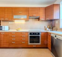 A kitchen with wooden decor, built-in appliances, and a microwave in a 2-room apartment.