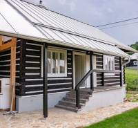 A cottage in Legnava with a wooden facade and a paved terrace, surrounded by greenery and nature.