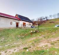 A family house in Klenovec on a slope, with a nearby bench and green surroundings.