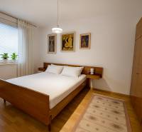 A bedroom in a 4-room apartment with wooden furniture, a floor with a wooden decor, and paintings on the wall.