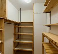 A simple wardrobe with wooden shelves and a hanging rod in a 4-room apartment.
