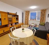 Living room in a 4-room apartment with a wooden decor floor, stylish furniture, and a dining table.