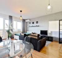 Living room in a one-room apartment with a wooden decor floor, a sofa, and a television.
