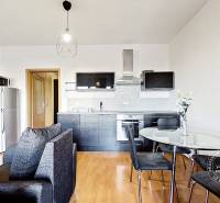 Interior of a 1-room apartment with a wooden decor floor, kitchen, and dining table.