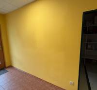 Yellow wall and glass doors in commercial space with brown flooring.
