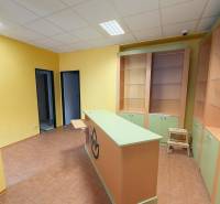 Yellow walls, counter, shelves, and tiles in commercial spaces with wood-patterned flooring.