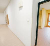 A white corridor in commercial premises with wood-patterned flooring and a room with tiles.