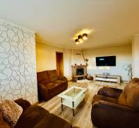 Living room of a three-room apartment with a wooden decor floor and comfortable seating furniture.