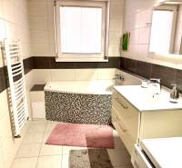 Bathroom with a bathtub, sink, washing machine, and tiles in a 3-room apartment.