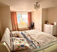 A bedroom in a 3-room apartment with a bed, a wardrobe, and a window with orange curtains.