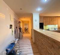 A hallway with a wooden decor floor leads to the kitchen in a three-room apartment.