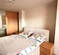 Bedroom with a bed, built-in wardrobe, and decorative chandelier in a 3-room apartment.