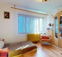 A room in a family house with a wooden decor floor, a sofa, and a cabinet.