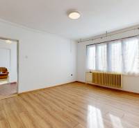 A spacious room in a family house with a wooden decor floor and a large window.
