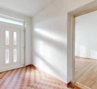 Entrance hall in a family house with white walls, tiles, and a floor with a wooden decor.