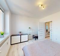 A bright bedroom in a three-room apartment with a wooden decor floor and minimalist furnishings.