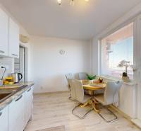 A kitchen in a 3-room apartment with a dining table and a floor with a wooden decor.