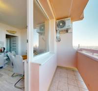 A kitchen with a dining area and a balcony in a 3-room apartment with a wooden decor floor.