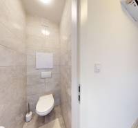 A small bathroom with light tiles and a wall-mounted toilet in a 3-room apartment.