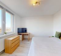 Bright bedroom with a bed and a television, wooden decor flooring, 3-room apartment.