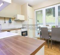 A kitchen in a 2-room apartment with a wood-patterned floor, a dining table, and appliances.