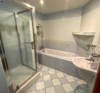 A bathroom in a 3-room apartment with a shower, a bathtub, and light-colored tiles.