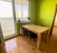 A bright dining room with a wooden table and a floor with a wooden decor in a 3-room apartment.