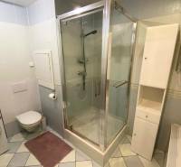 A bathroom in a 3-room apartment with a washing machine, shower, and white furniture.