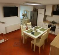A kitchen in a family house with a tiled floor, a dining table, and a kitchen unit.