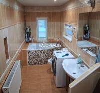 Bathroom with a bathtub, sink, and washing machine in a family house. Soft tones and ceramic tiles.