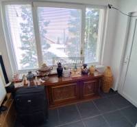 A room with a large window, a decorative dresser, and various items in a family house.