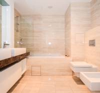 Bathroom with a bathtub, bidet, and double sink in a 3-room apartment. Light tiles dominate the space.