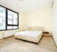 Bedroom with a bed, nightstands, and large windows, floor with wood decor.