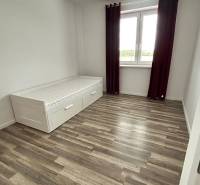 A room with a bed, a wooden floor decor, and a large window in a 3-room apartment.